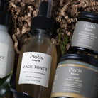 Close-up of Piotis Naturals eco-friendly skincare products, including the Natural Rosewater Face Toner in a glass bottle with aluminium lid, Heliaktída Weightless Touch Mineral Sunscreen, and Arkhé Calming Cream for dry skin and eczema. All products are vegan, cruelty-free, and packaged in glass jars with recyclable aluminium lids, reflecting a commitment to natural, sustainable skincare.