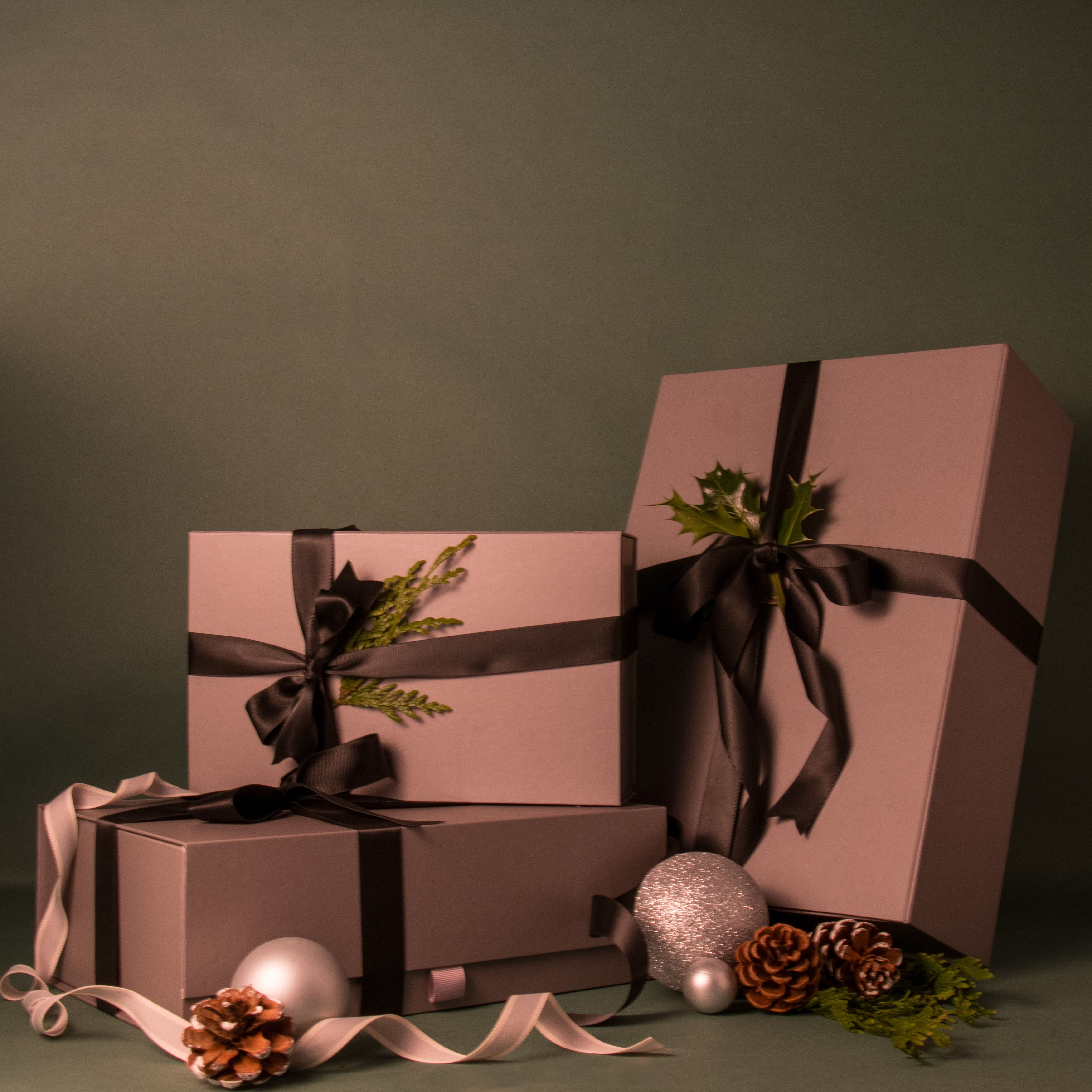 Piotis Naturals luxury grey gift boxes for skincare and haircare, tied with black fabric ribbons and adorned with greenery, available in three sizes (medium, large extra large). Premium magnetic clasp packaging perfect for Christmas gifting.