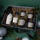 Piotis Naturals medium Christmas gift box featuring vegan, cruelty-free, and natural skincare made in Norwich, UK. Includes the One Step Aloe Gel Cleanser, Natural Rosewater Face Toner, Arkhé Calming Cream for dry and eczema-prone skin, Heliaktída Mineral Sunscreen, Metastrophé Anti-Ageing Day Cream, and Péplo Anti-Ageing Night Cream. Elegantly presented with black fabric ribbon, eco-friendly shredded paper, festive greenery, and silver baubles.